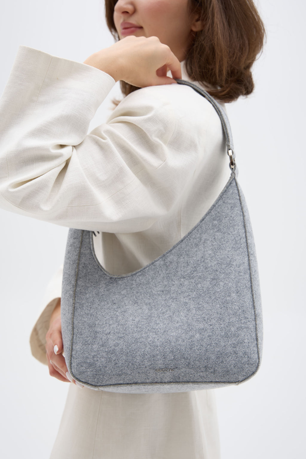 Person holding a silver shoulder bag against a white background