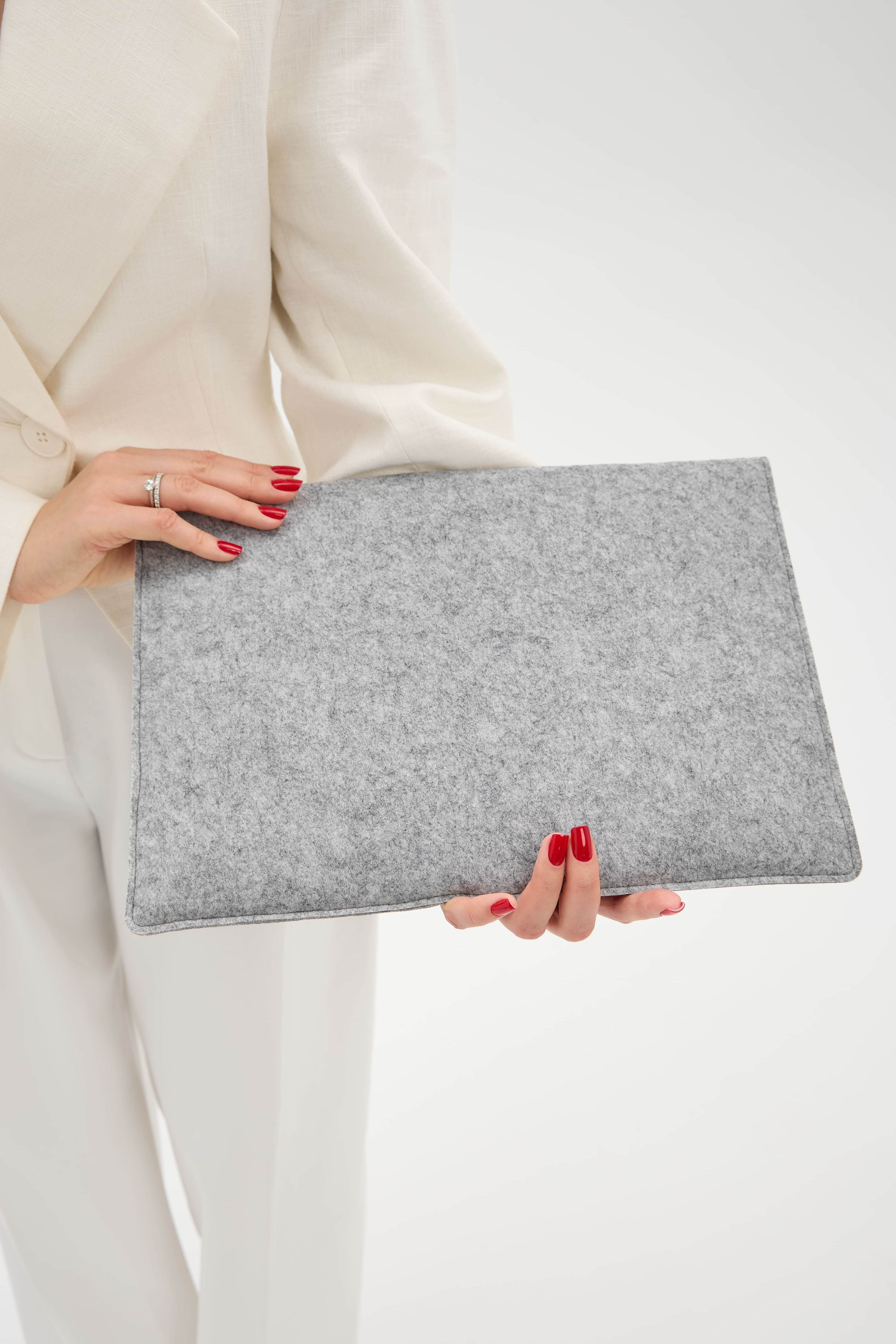 Person holding a silver felt case against a white background